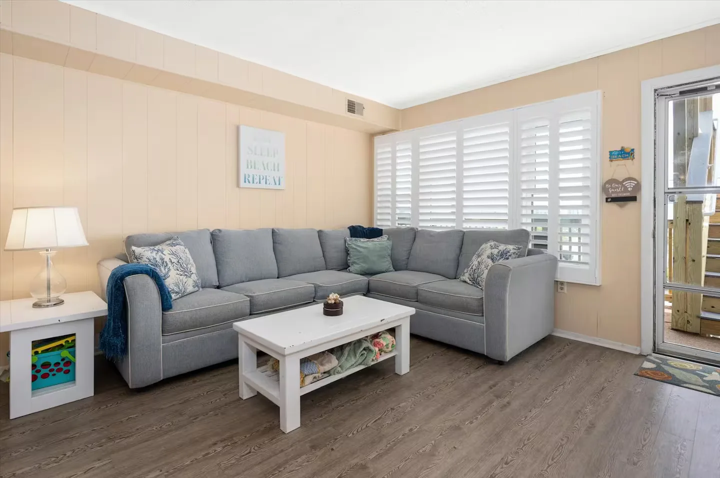 The bright, open living room — plantation shutters and a queen sleeper sectional